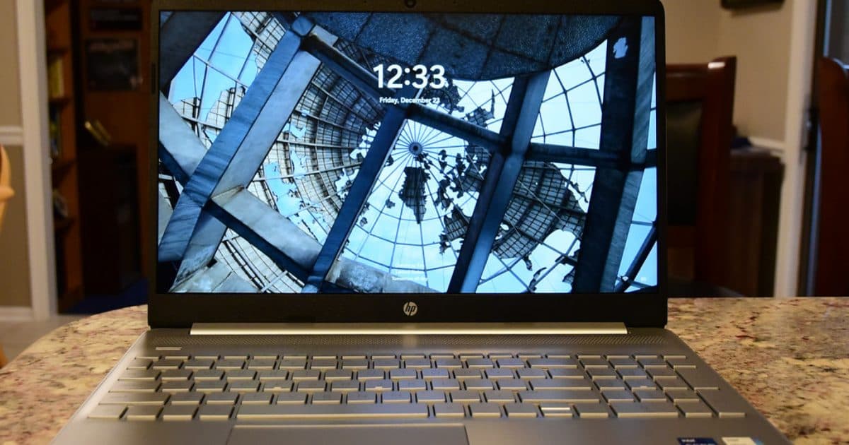 En bärbar HP-dator på ett köksbord, med Windows 11:s låsskärm på skärmen.